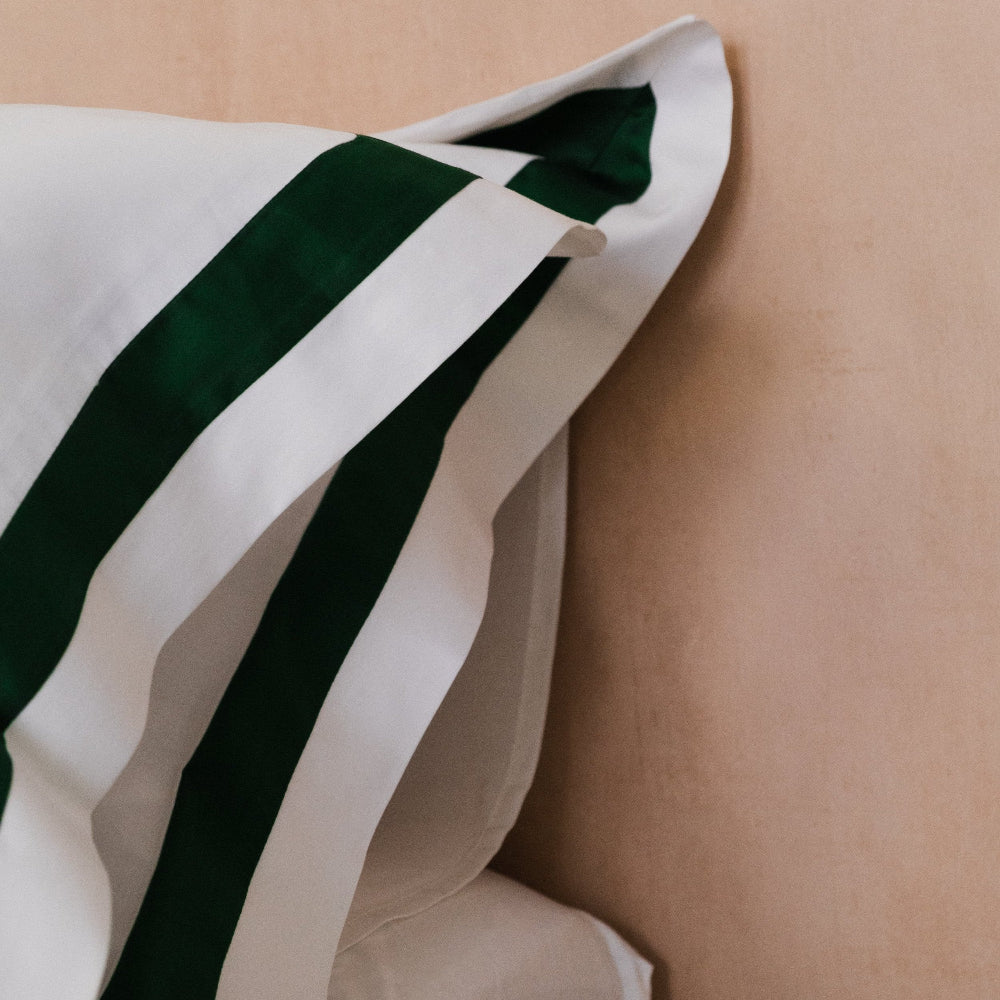 Close-up of a white pillow with green stripes on a beige background