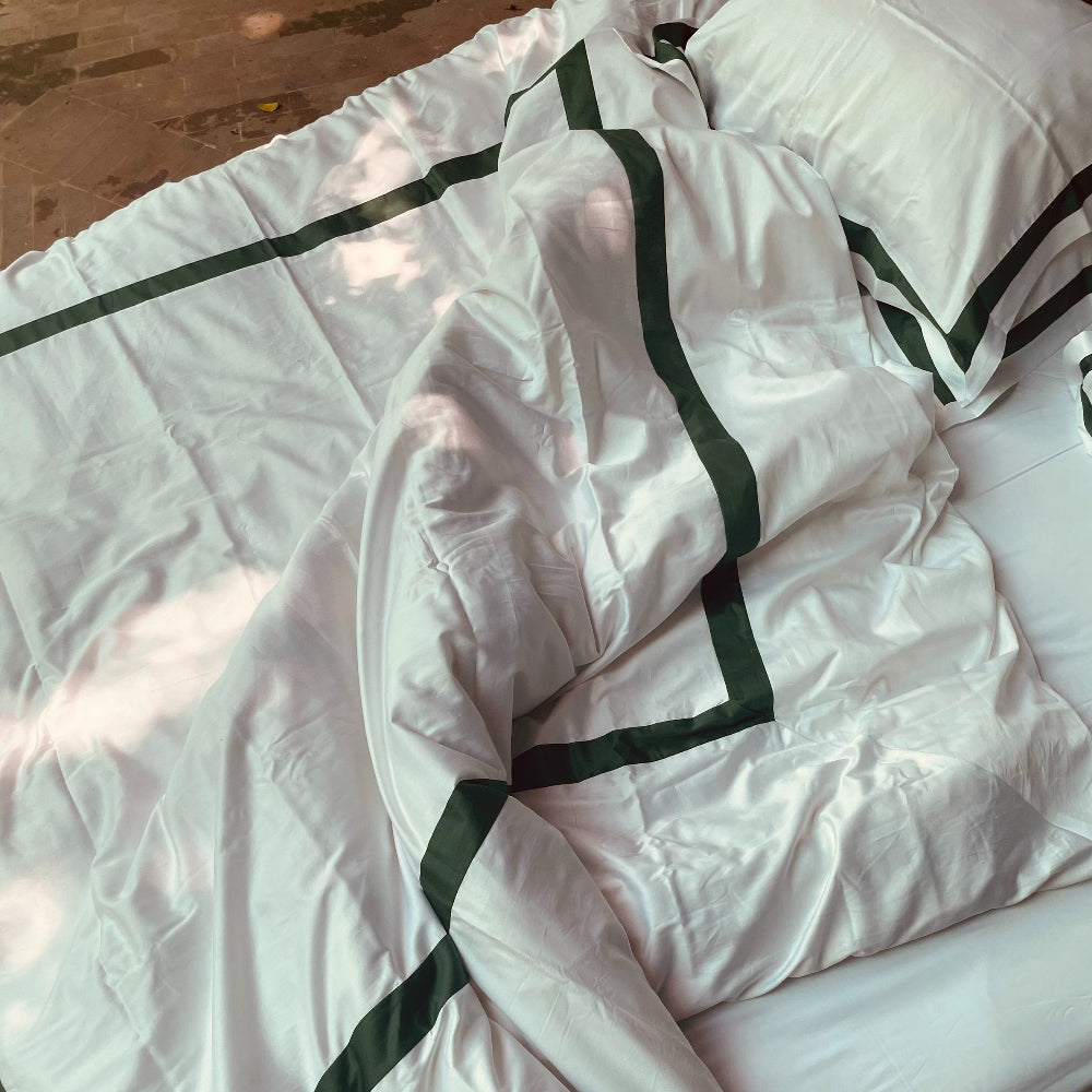 Sukun Notting Hill London Green and White bedding with green trim on a bed