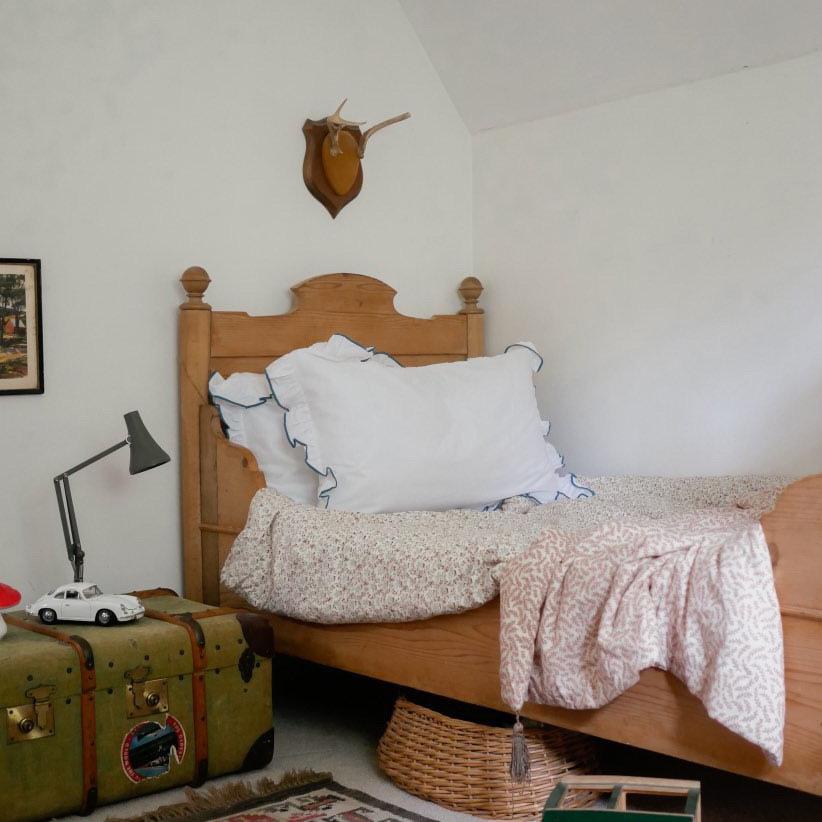 Bedroom with wooden bed, vintage suitcase, and wall-mounted deer head.
