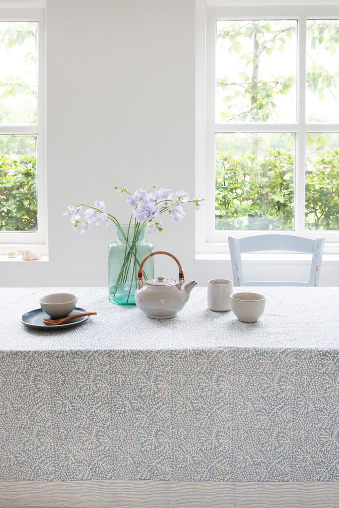 Kitchen Dining Table with tea set and flowers near a window with a view of greenery