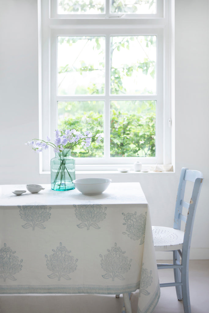 Dining room with a table, chairs, and a vase of flowers near a window.