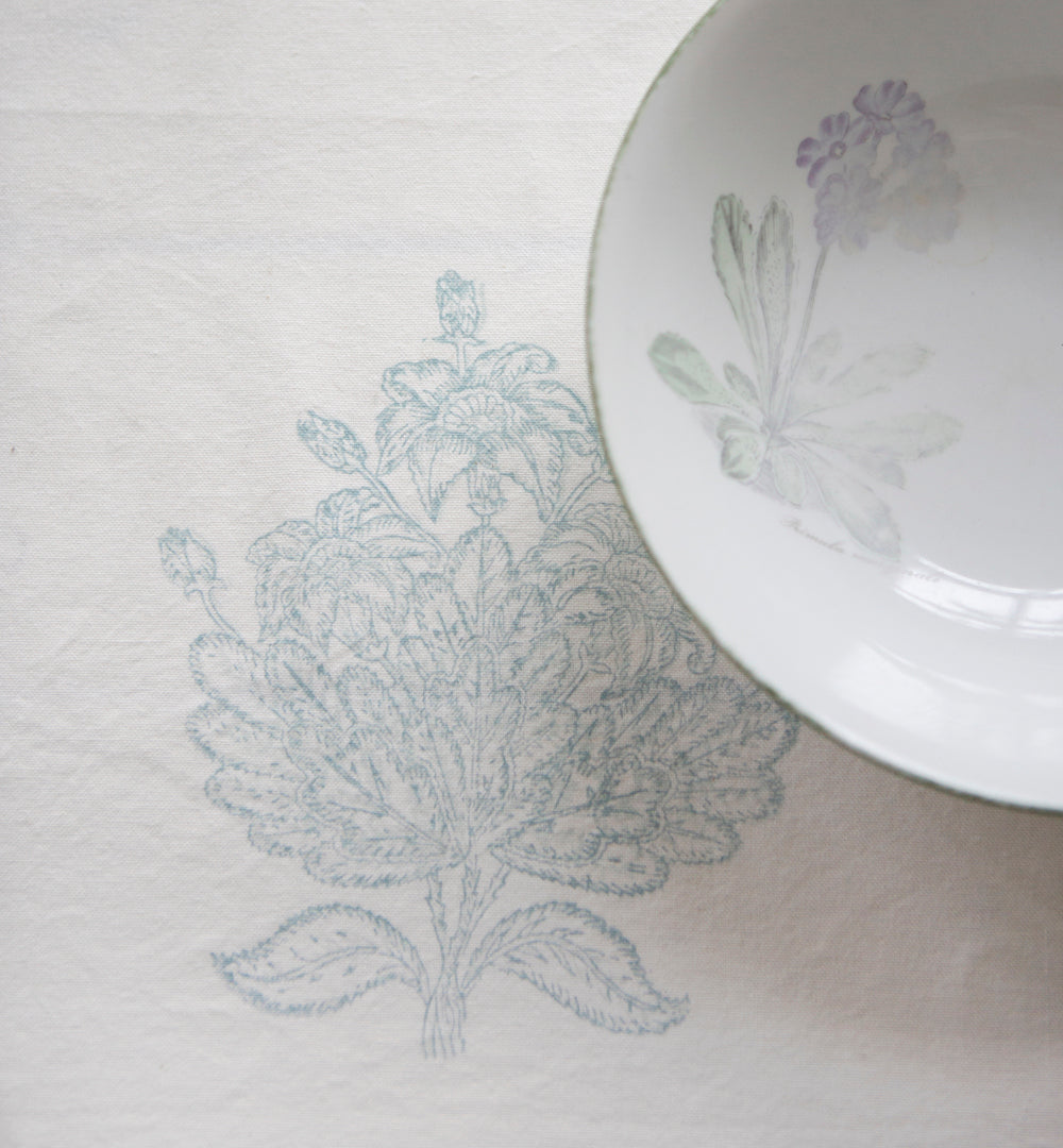 White ceramic plate with floral design on a matching white Tree of Life Tablecloth