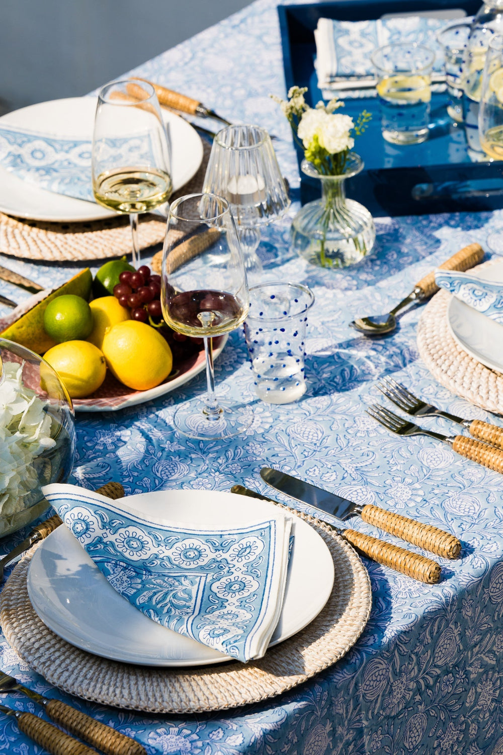 Dining table set with blue and white tablecloth, plates, glasses, and silverware.