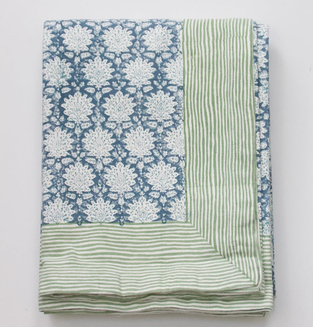Tablecloth with blue floral pattern and green striped border on a white background