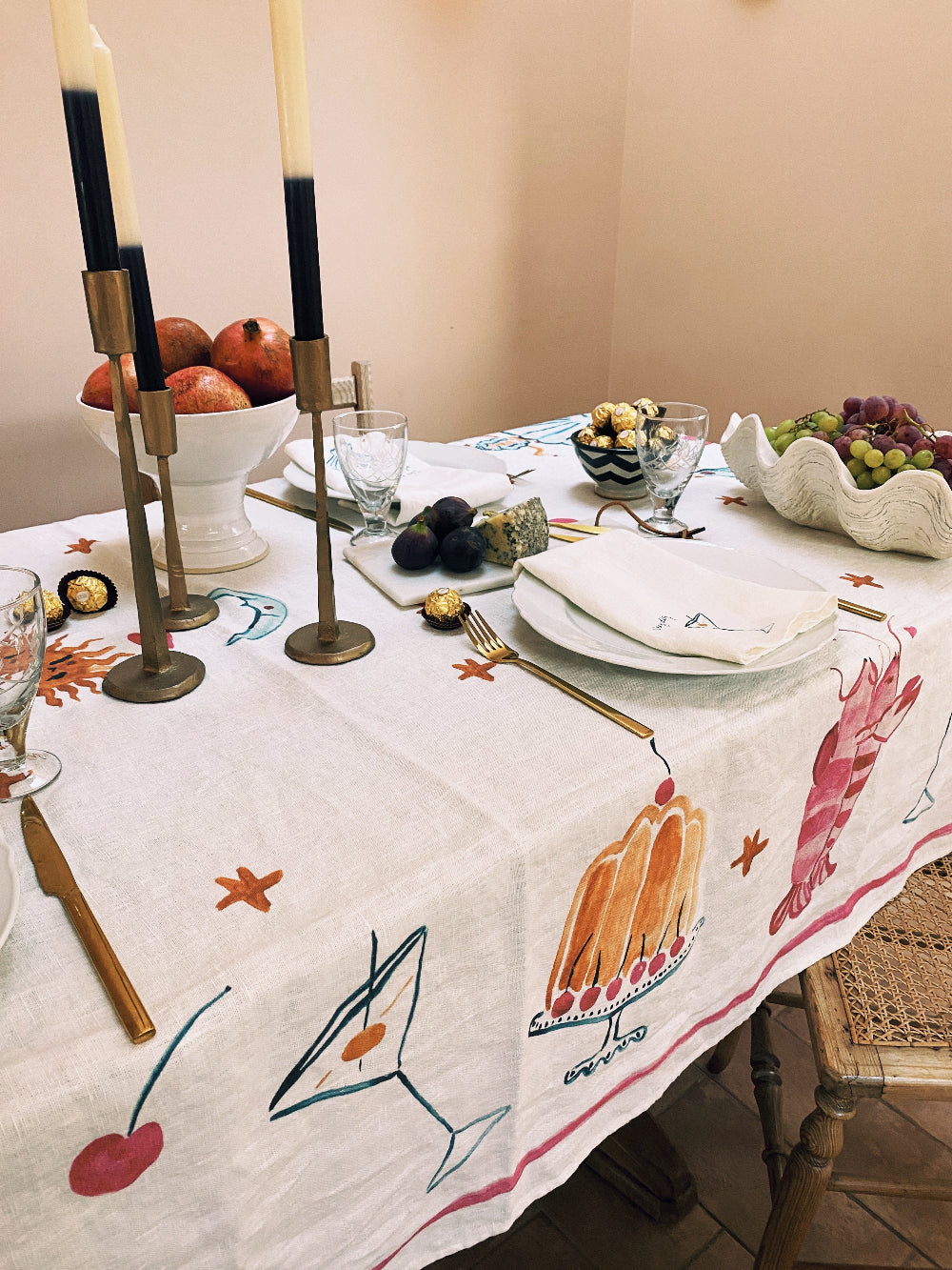 Dining table set with a decorative tablecloth featuring artistic designs.