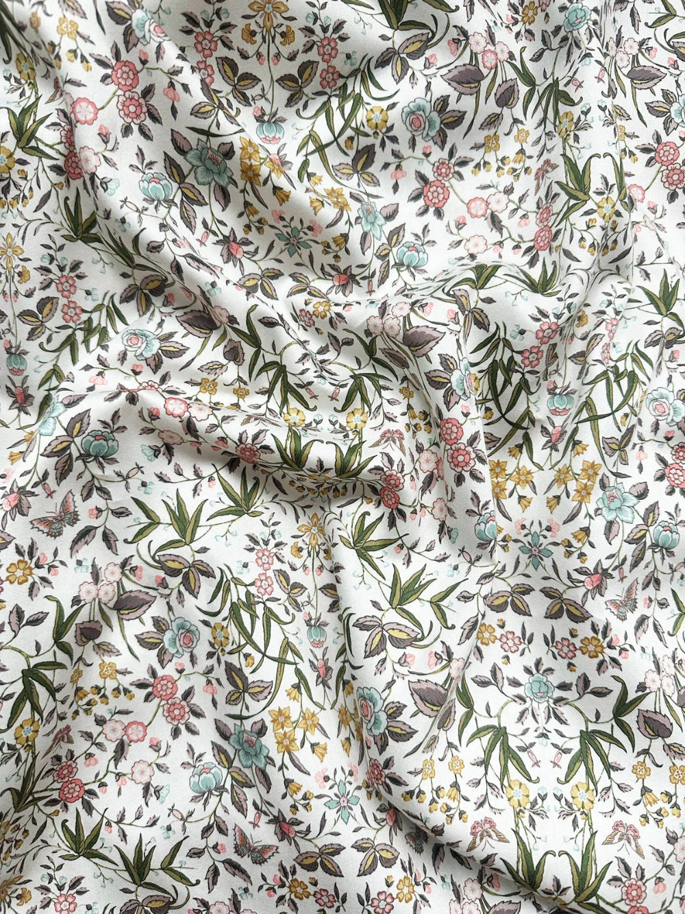 Floral fabric pattern with green leaves and pink flowers on a white background