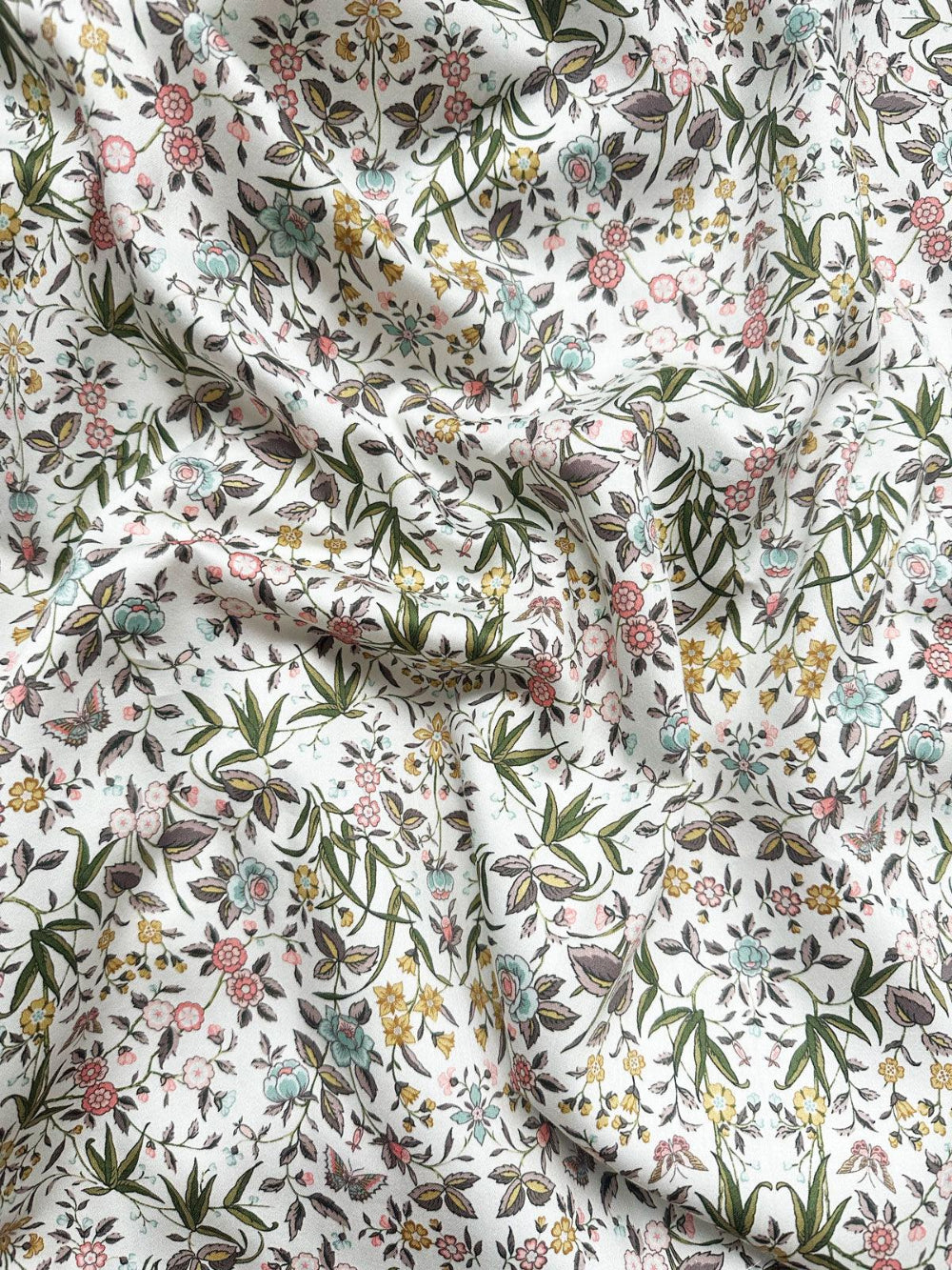 Floral and leaf patterned Liberty bedding fabric with a white background
