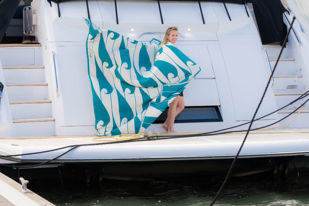 Woman holding a large turquoise and white patterned towel on a boat