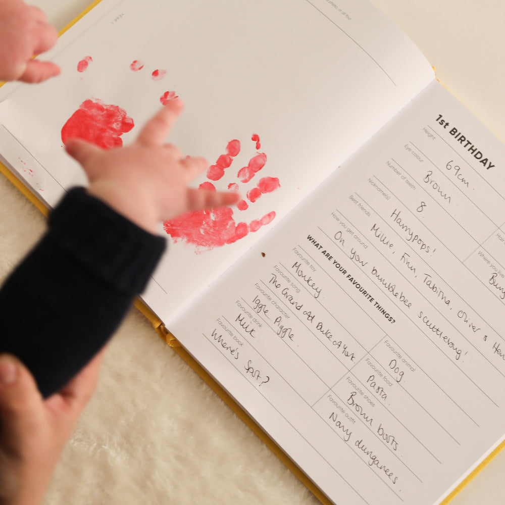 Child's Hand holding a book with red handprints on a white background