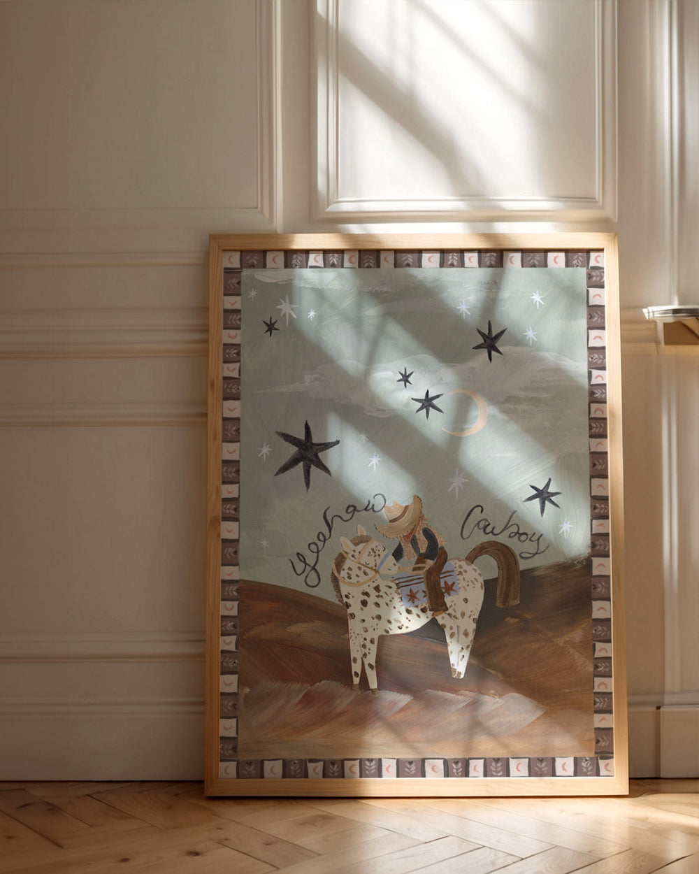 Framed artwork of a cowboy on a horse with stars above, on a wall.