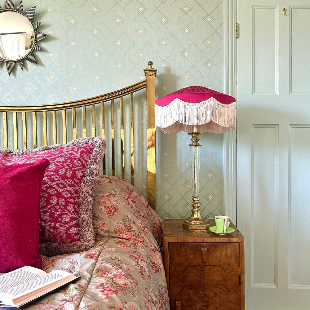 Bedroom with floral bedding, pink pillows, and a Fringed Pink lamp on a nightstand.