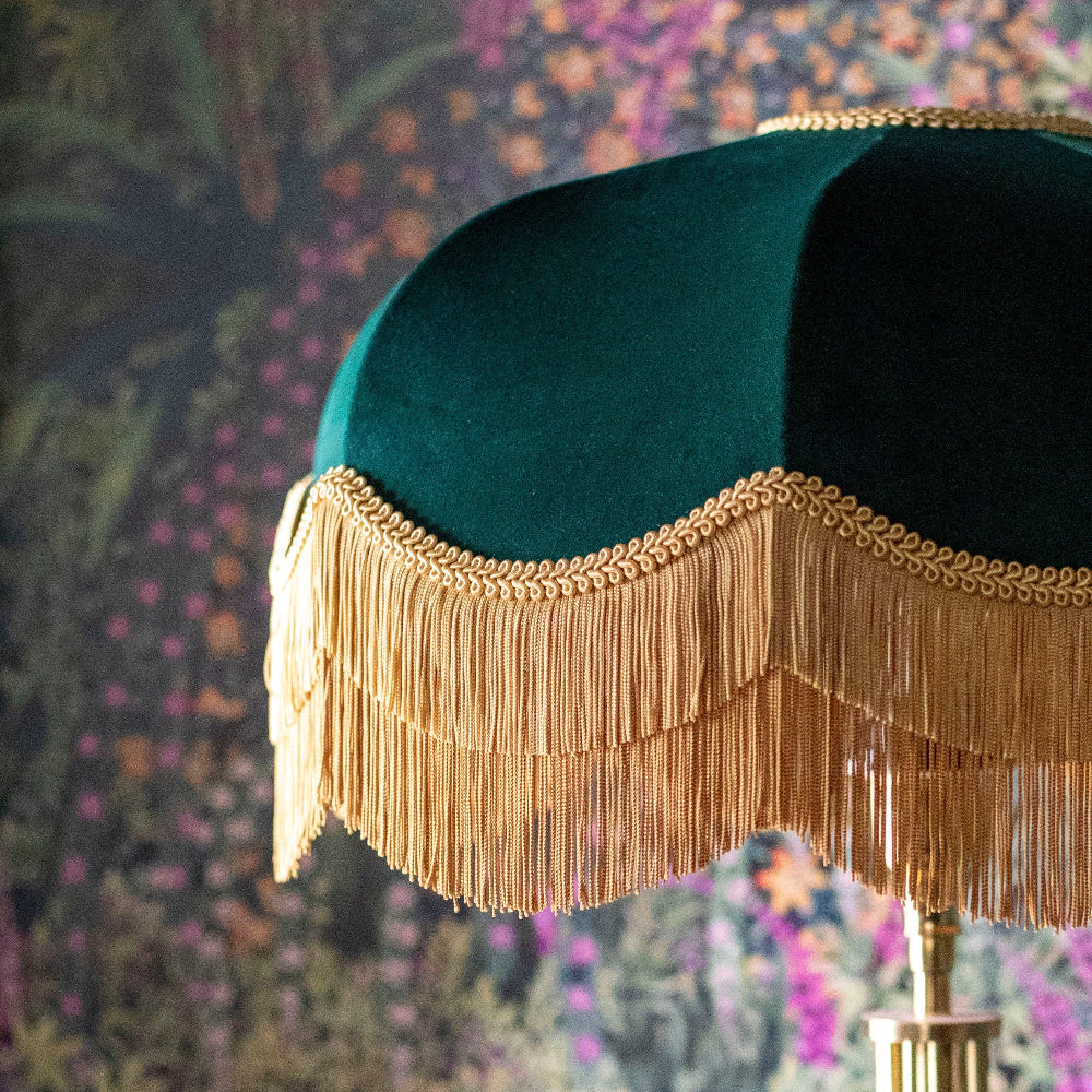 Emerald Lampshade with gold fringe against a floral-patterned wall.