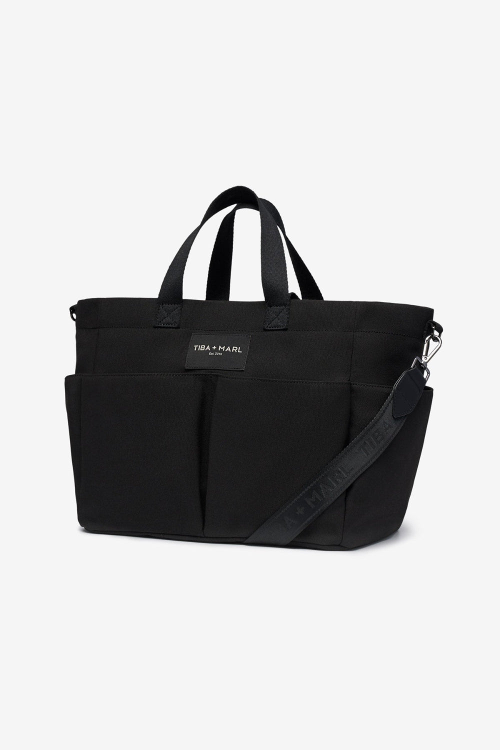 Black tote bag with a visible brand label Tiba + Marl on a white background with straps extended