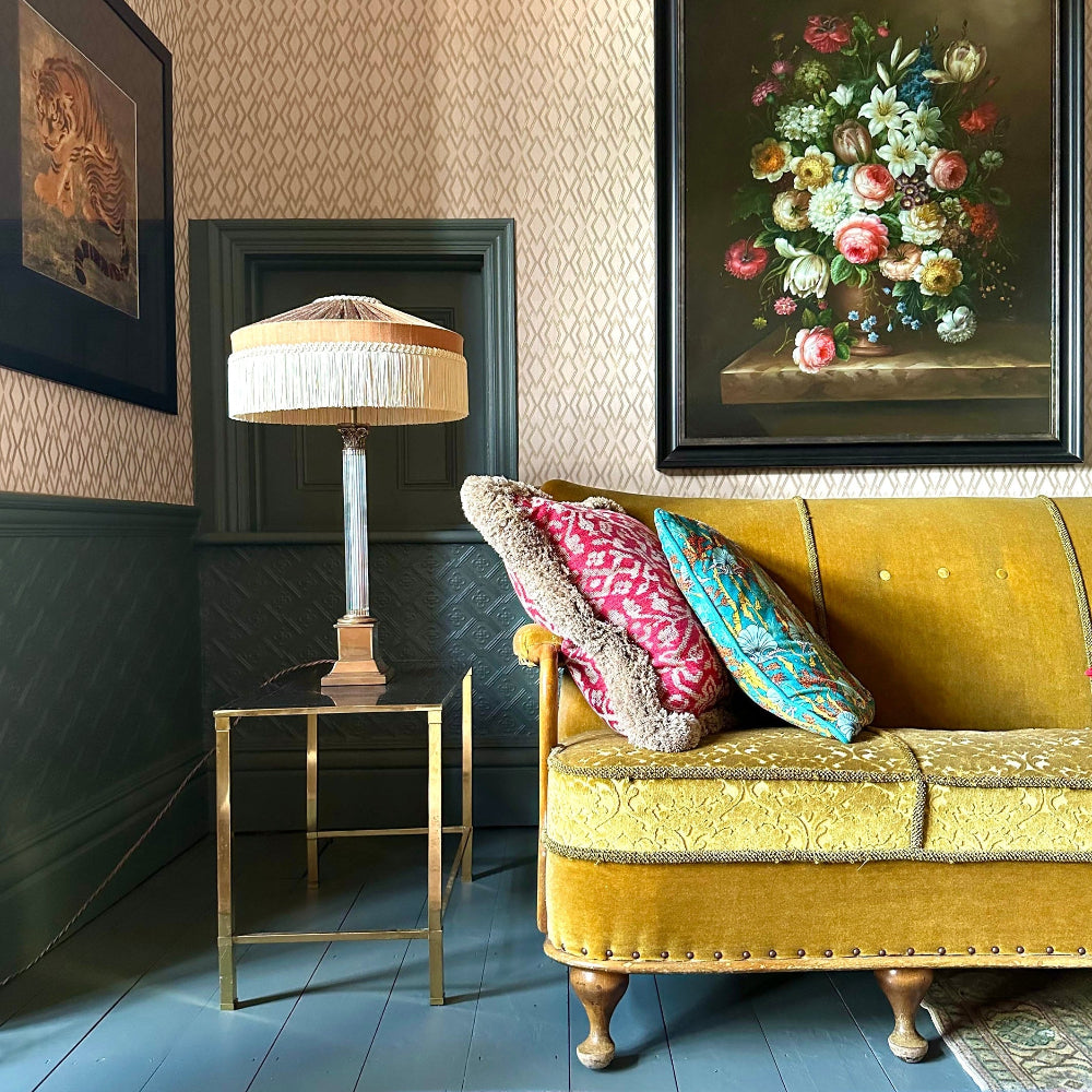 Living room with yellow velvet sofa, floral painting, and Peggy Silk Fringed lampshade.