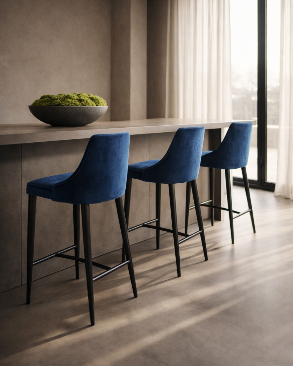 Three blue bar stools in front of a luxury bar table with a decorative bowl.