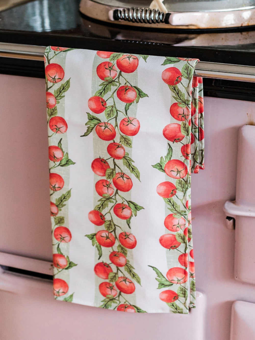 Kitchen towel with tomato pattern hanging on a stove handle