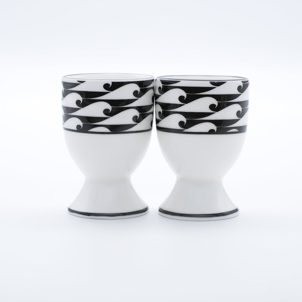 Two white egg cups with black wave patterns on a white background