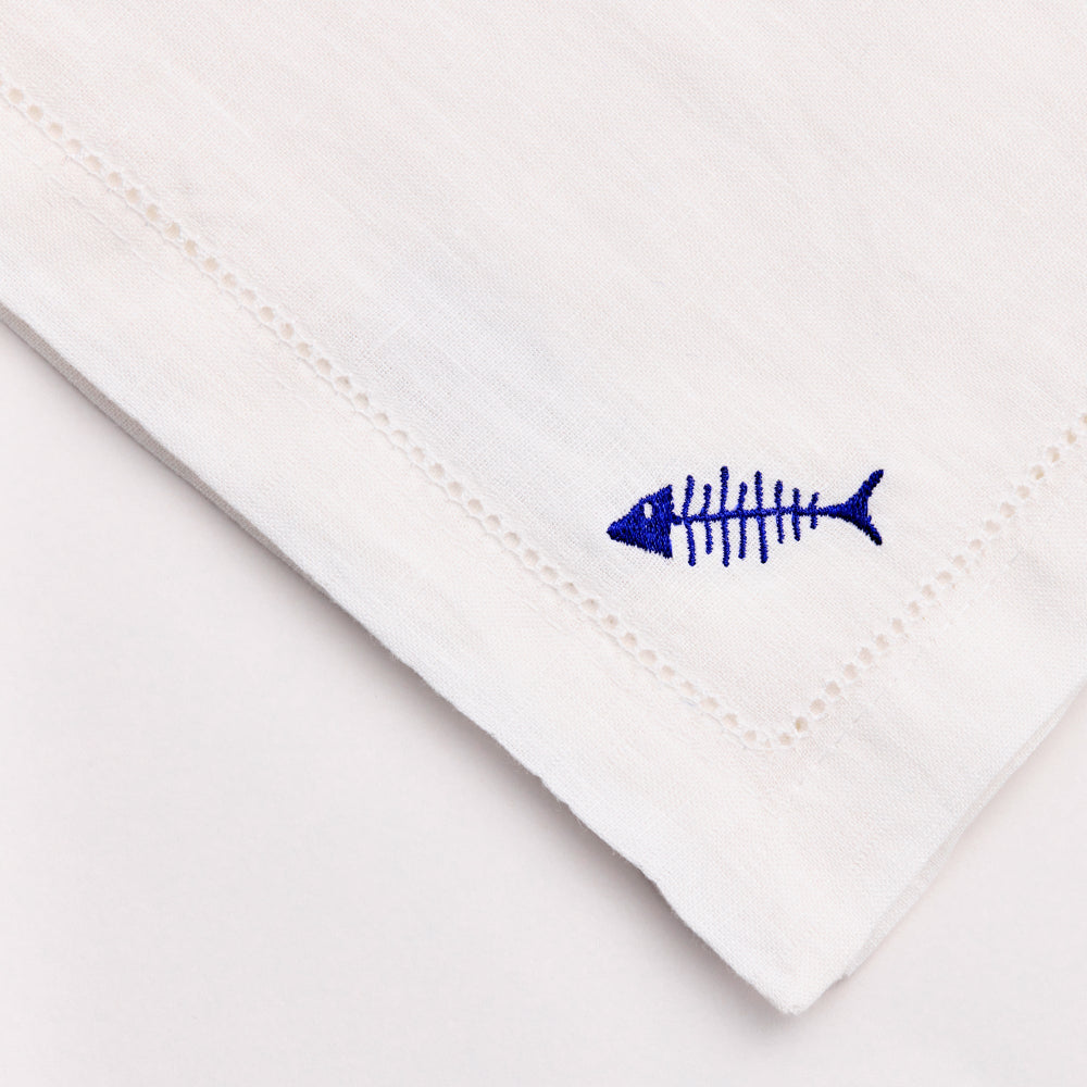 White hemstitched napkin with a blue fishbone design on a white background