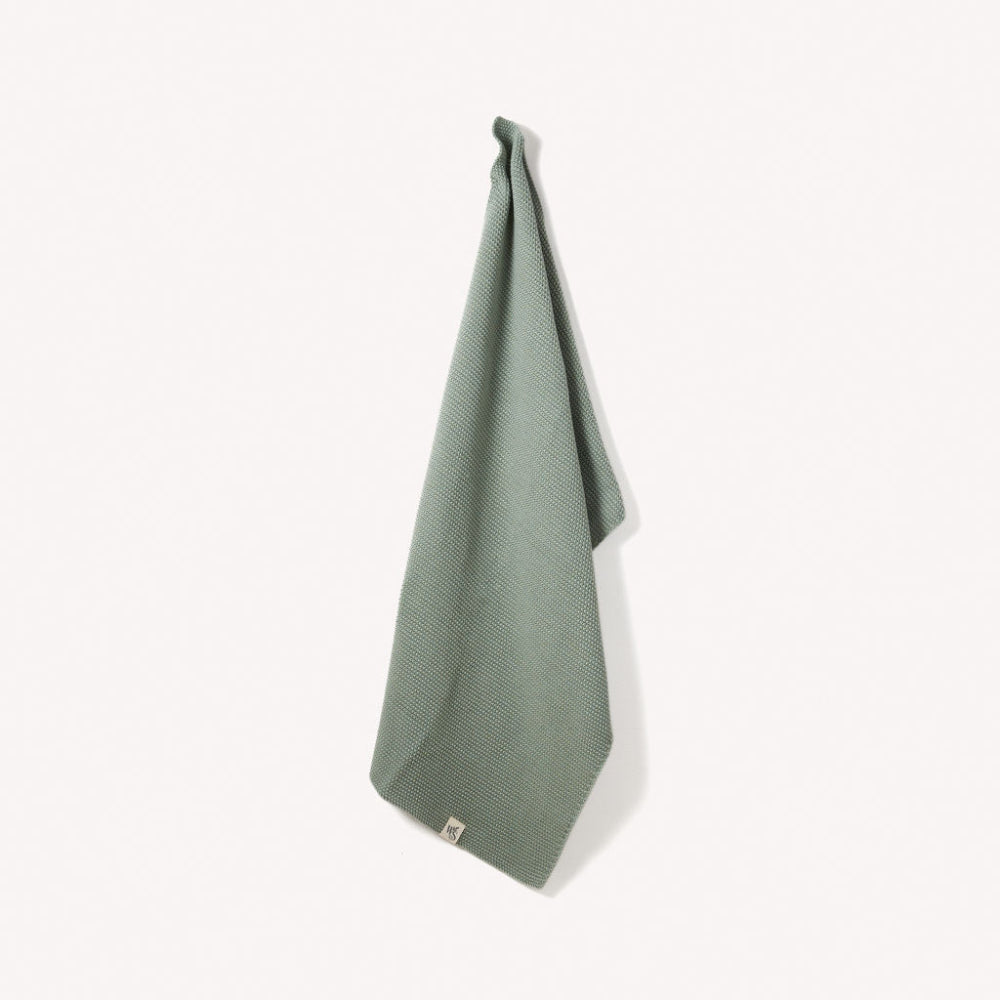 Green textured organic towel hanging on a white background