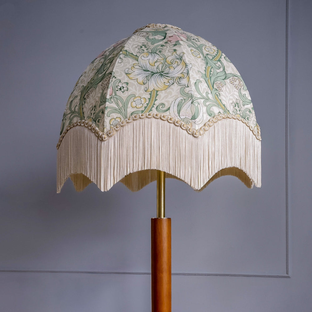 Decorative lamp with William Morris floral patterned shade on a plain background