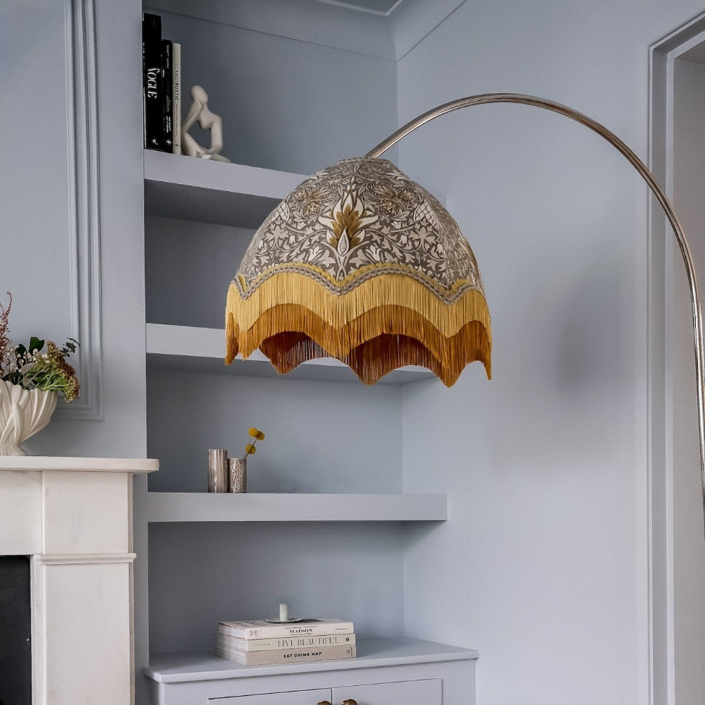 Decorative lampshade with intricate design hanging above a shelf in a room.