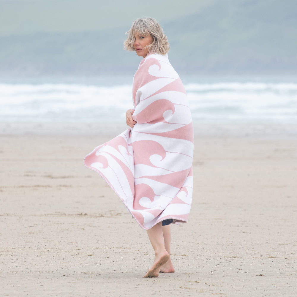 Woman wrapped in a pink and white patterned towel on a beach