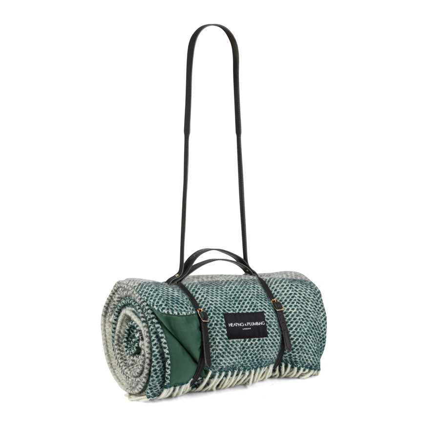 Roll-up picnic blanket with carrying strap on a white background