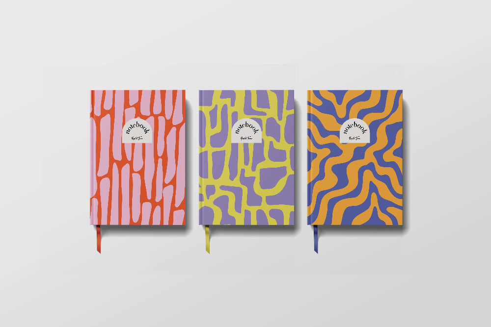Three colourful notebooks with abstract patterns on a light grey background