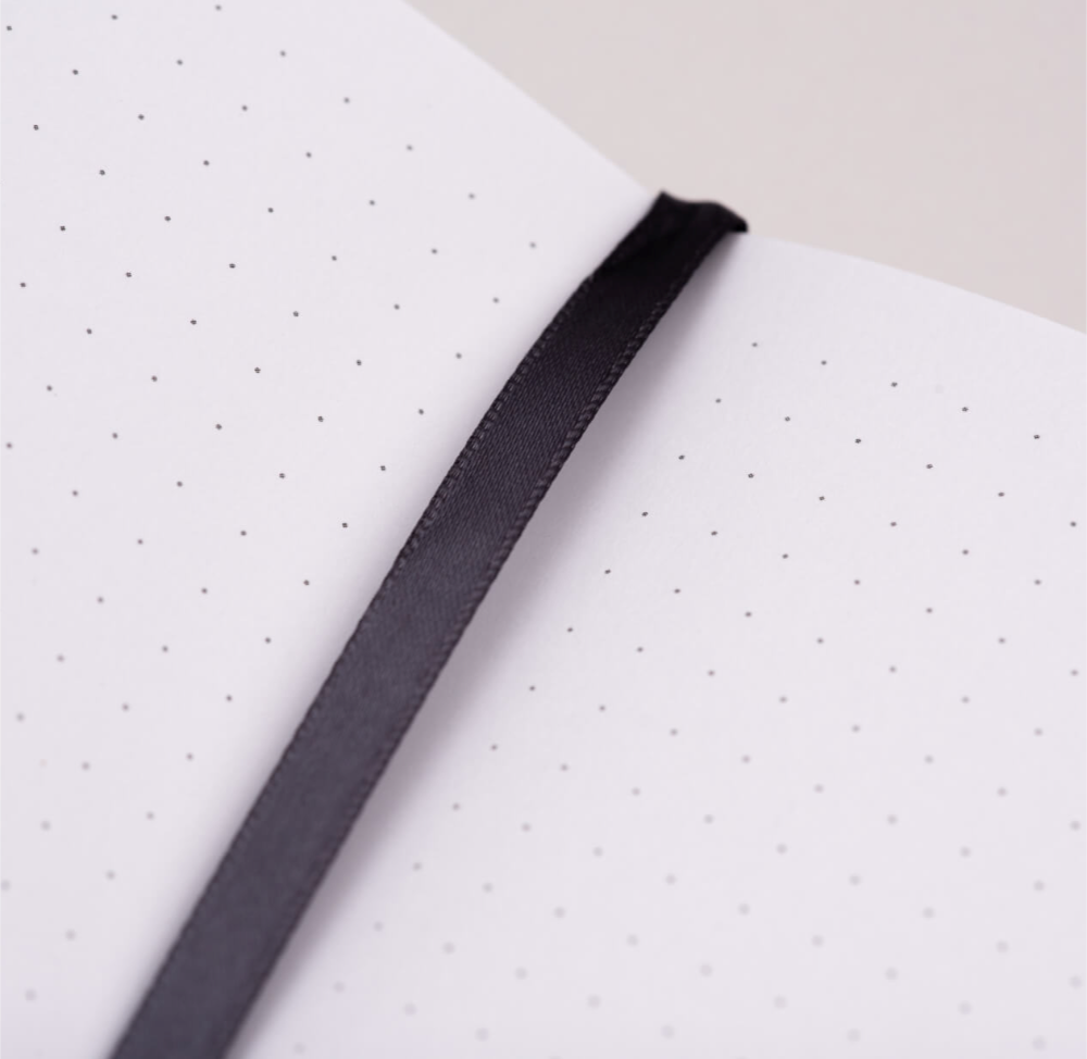 Black ribbon on a white notebook with black dots