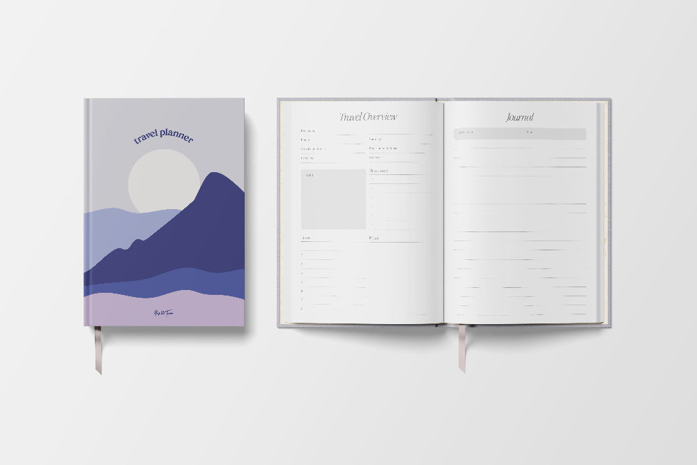 Journal with mountain design on cover and open to blank pages on a white background