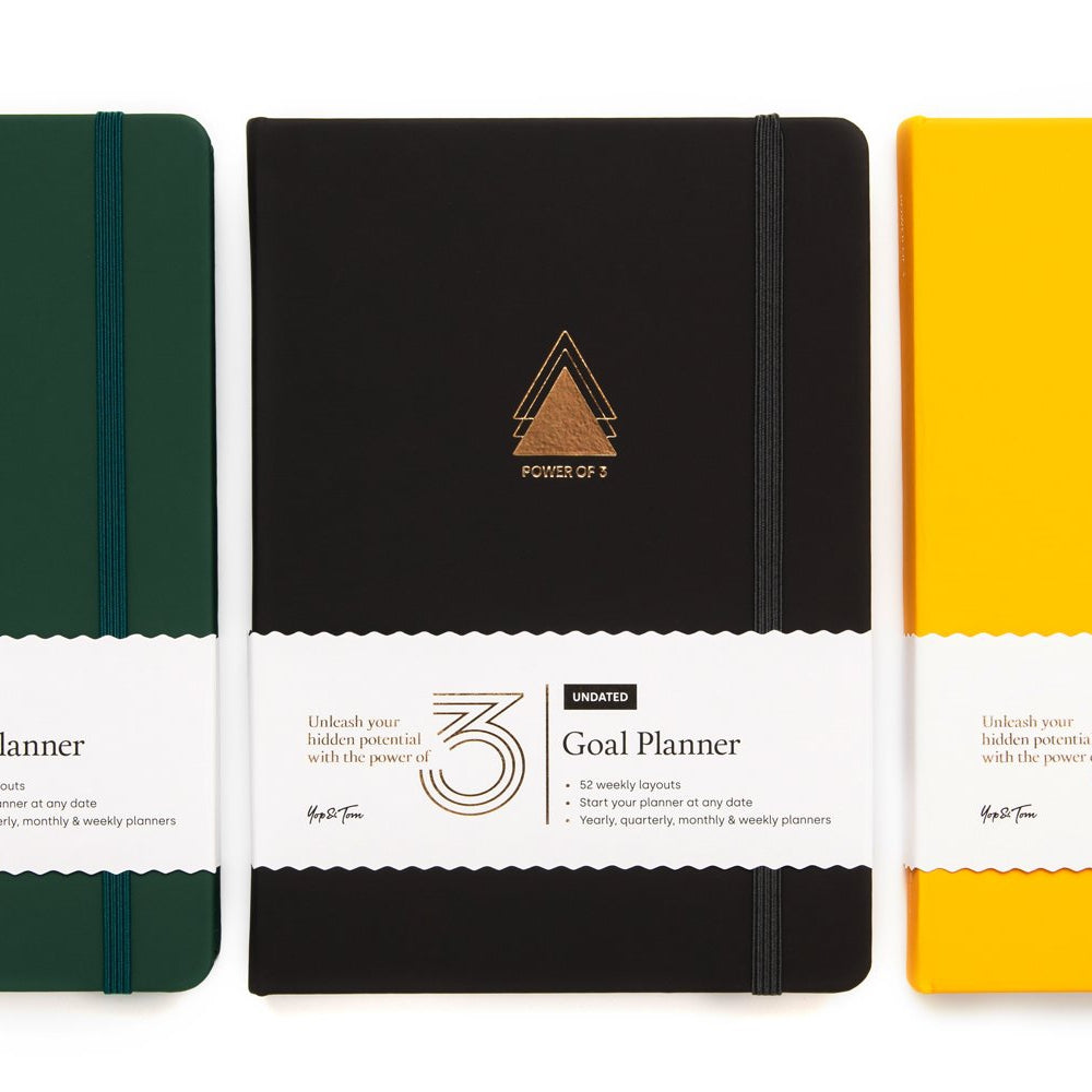 Three goal planners in green, black, and yellow on a white background