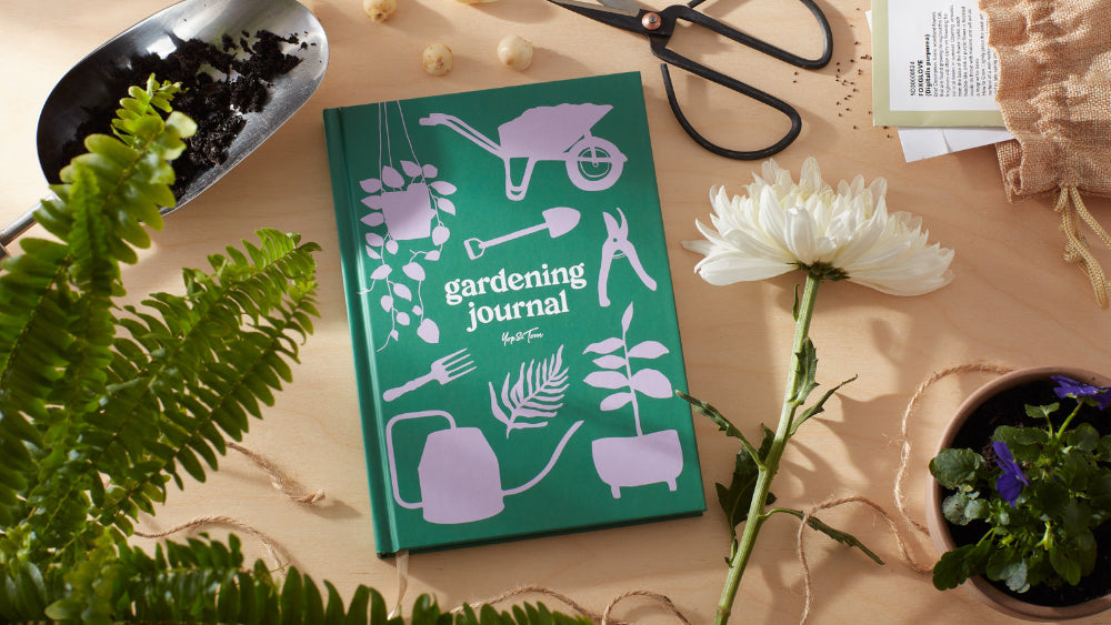 Green gardening journal with illustrations on a table with plants and tools