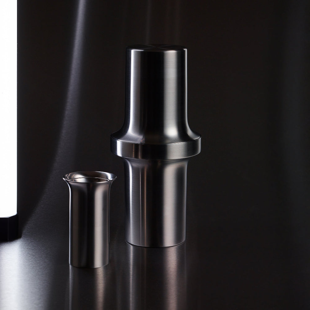 Aaron Probyn BARBICAN double-sided cocktail jigger shown beside its coordinating stainless steel shaker