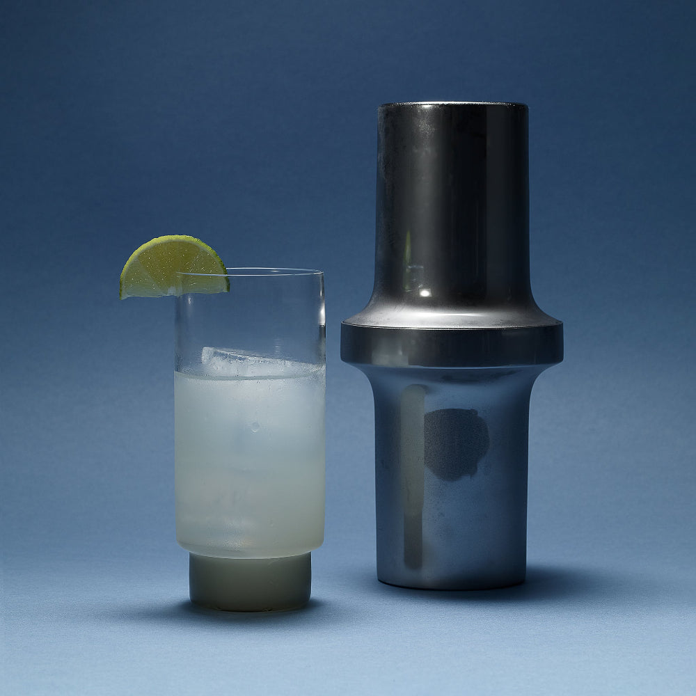 Aaron Probyn BARBICAN cocktail shaker beside a tall iced drink garnished with lime