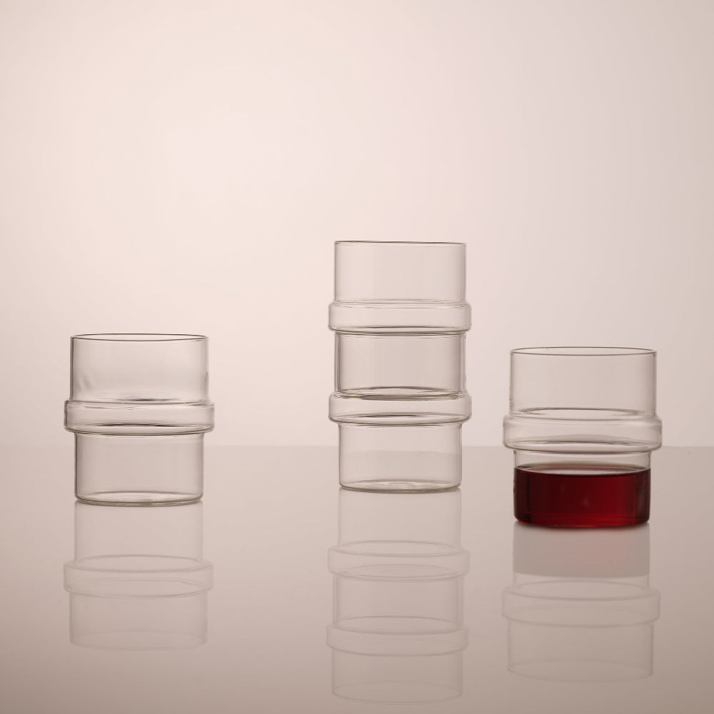 Aaron Probyn BLOCK clear drinking glasses stacked in groups with a red drink in one tumbler