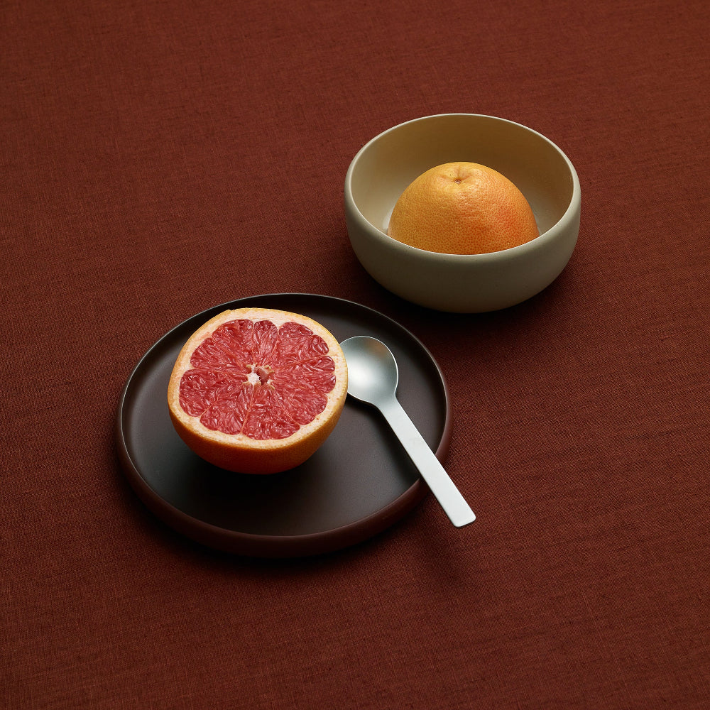 Brown COLOMBO side plate with half a grapefruit and a spoon on a terracotta-coloured surface
