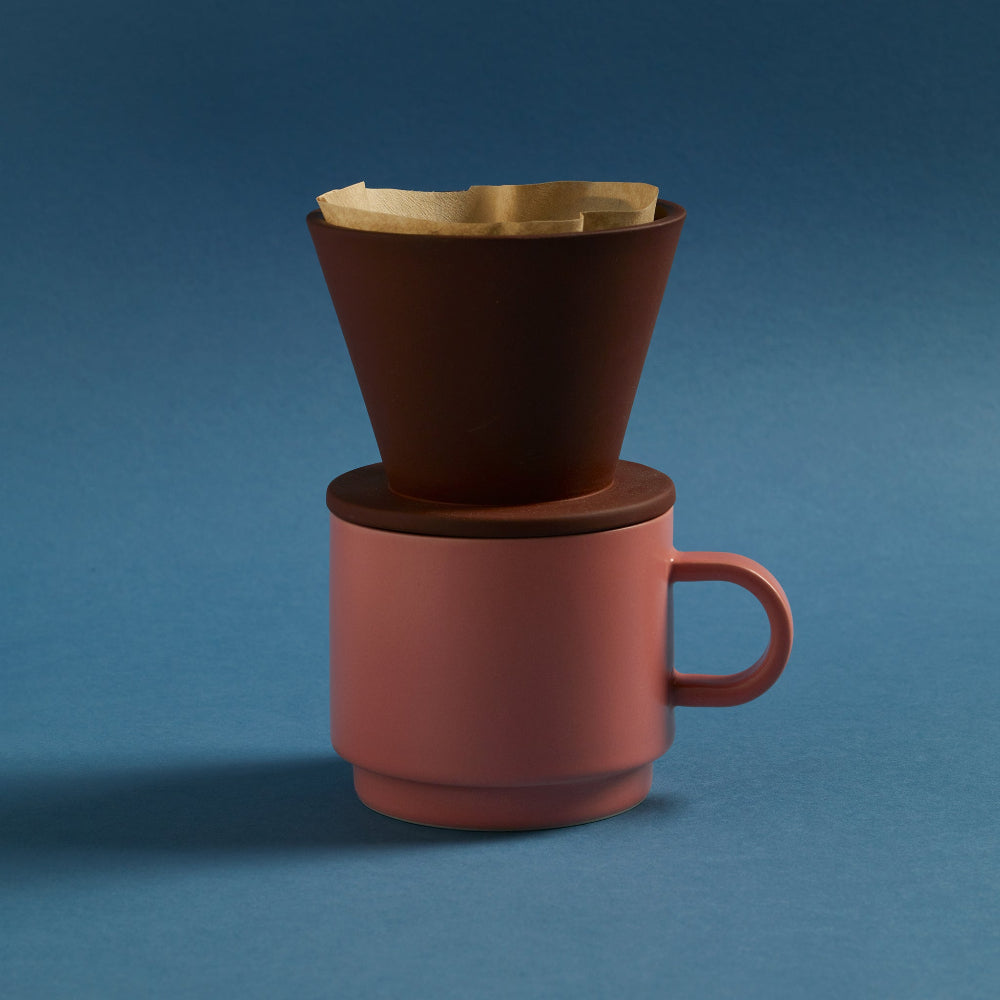 Terracotta porcelain coffee dripper by Aaron Probyn resting on a pink ceramic mug