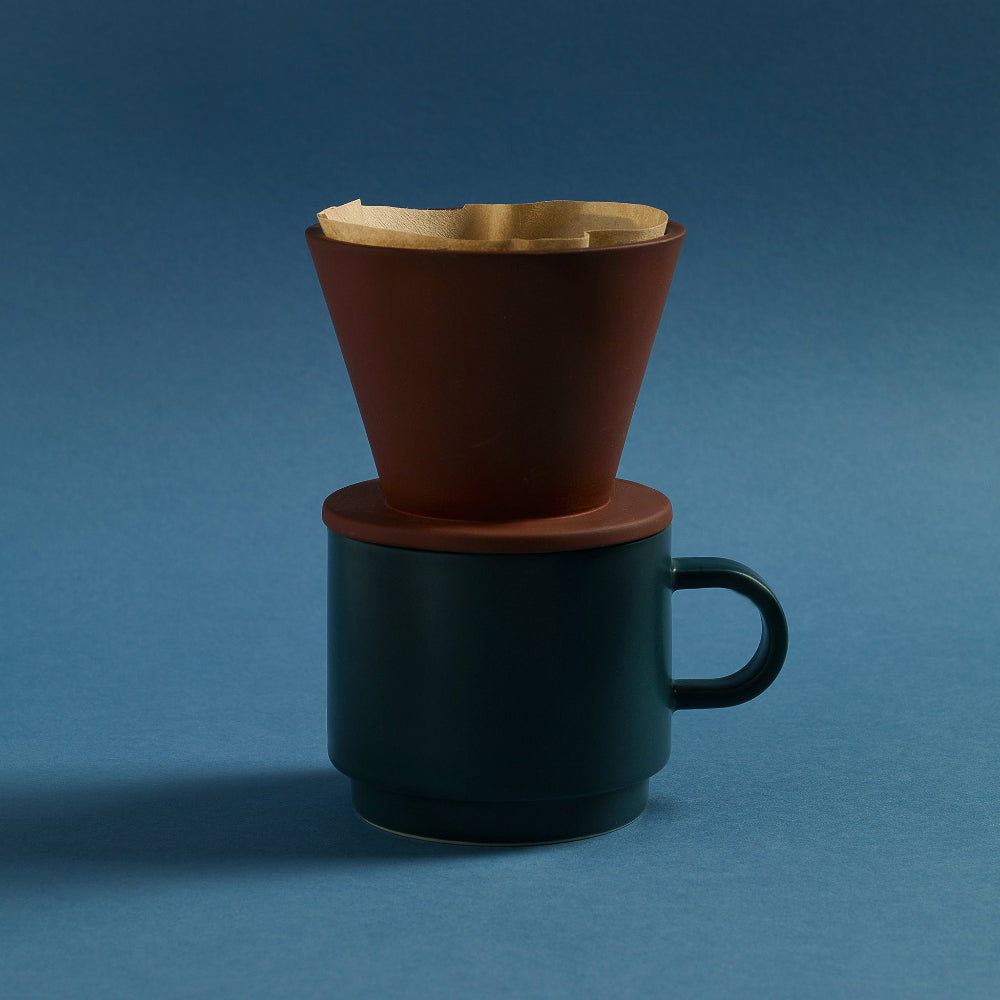Terracotta COLOMBO coffee dripper resting on a dark teal ceramic mug