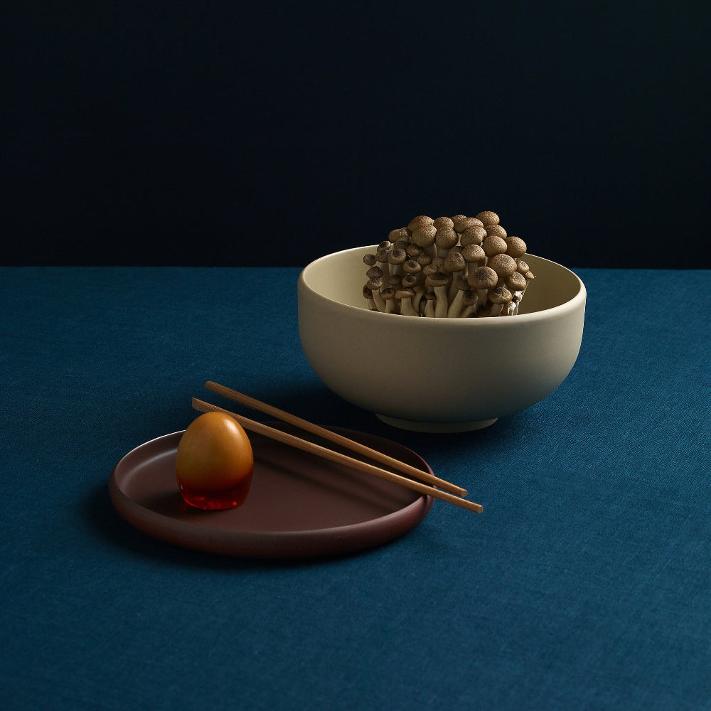 Aaron Probyn Oat porcelain ramen bowl filled with mushrooms, styled with a small plate and chopsticks