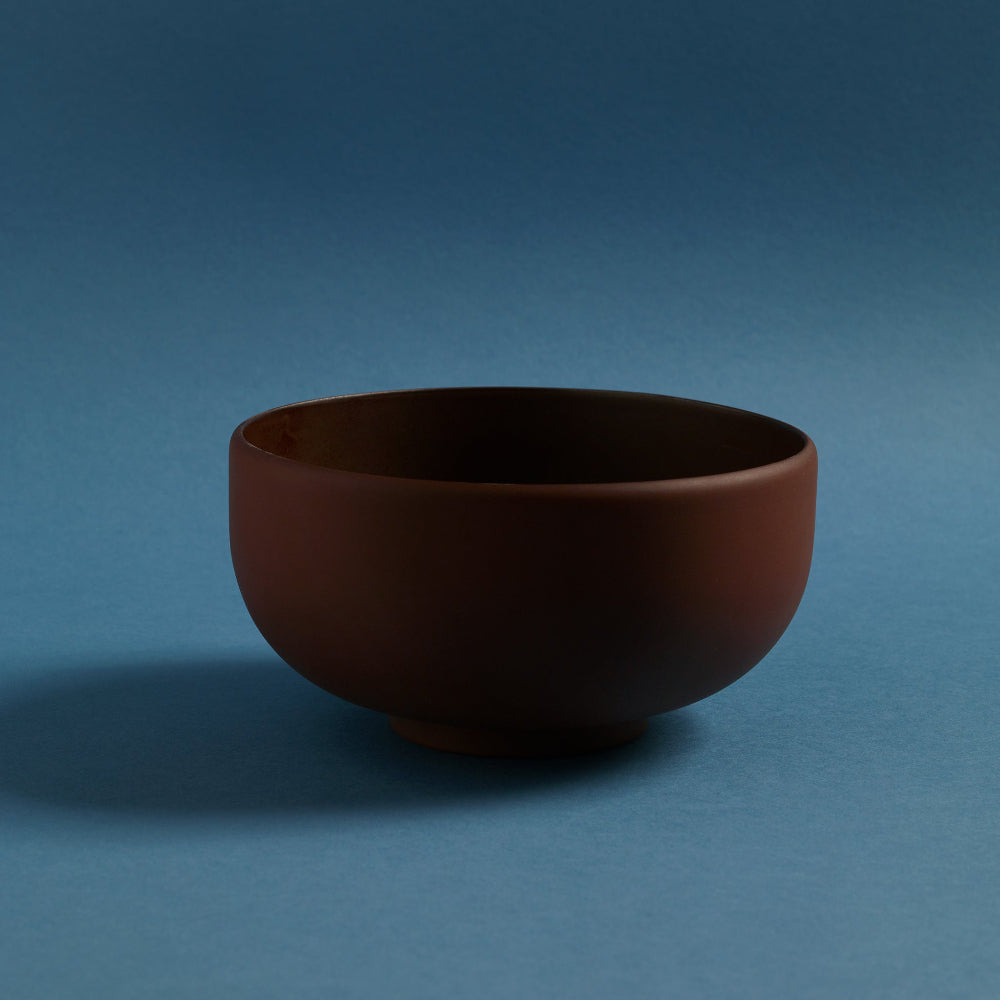 Aaron Probyn COLOMBO terracotta porcelain ramen bowl with rounded shape against a blue background