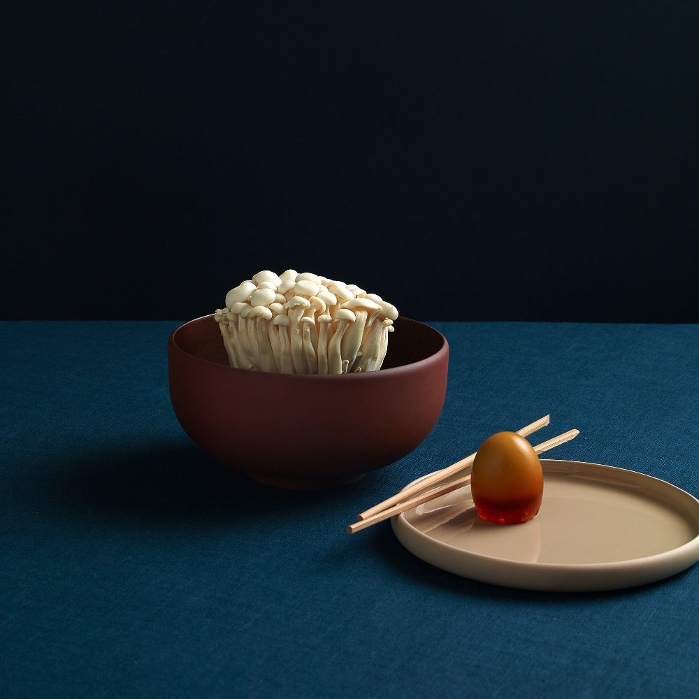 Aaron Probyn terracotta ramen bowl holding mushrooms beside a small plate and chopsticks