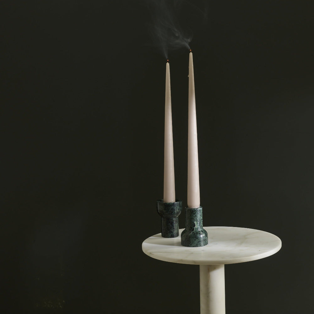 Two Aaron Probyn COMO Forest Green marble candle holders with tall pale taper candles on a white marble table