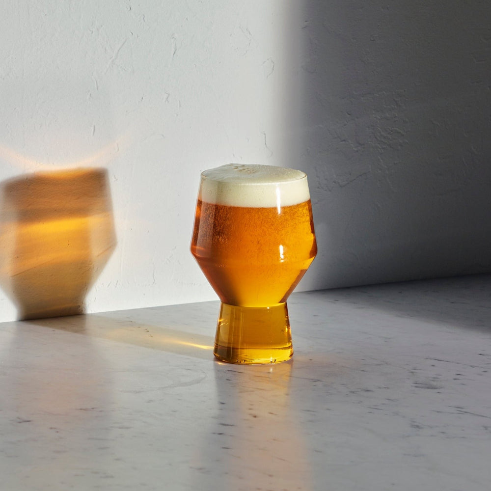 JUNIPER sculptural beer glass by Aaron Probyn filled with amber beer and a foamy head