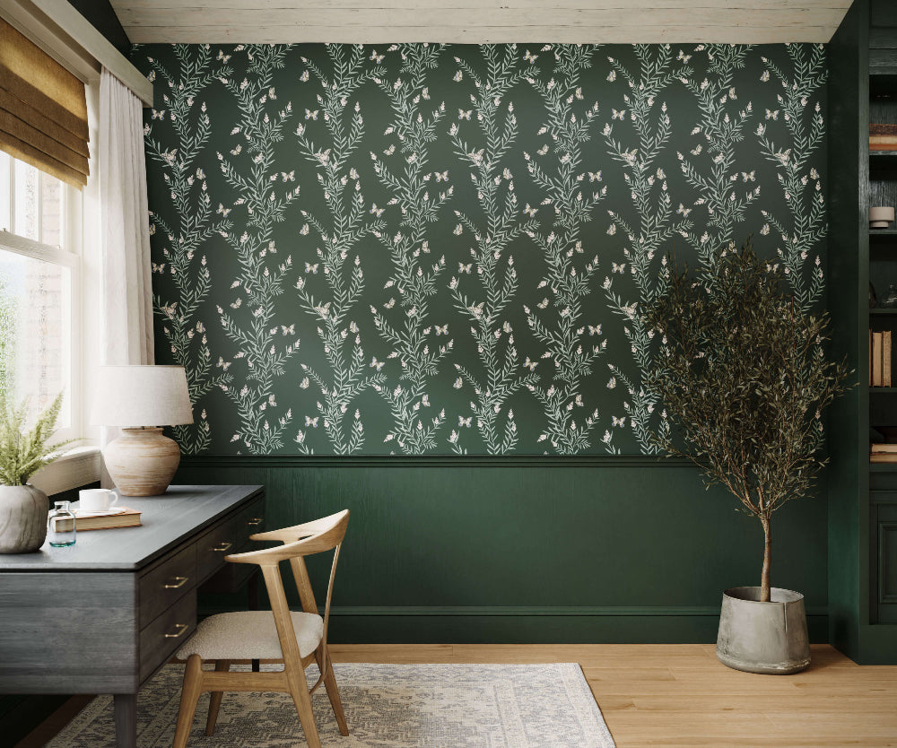 Room interior with a green wall featuring a floral pattern, a desk, chair, and decorative elements.