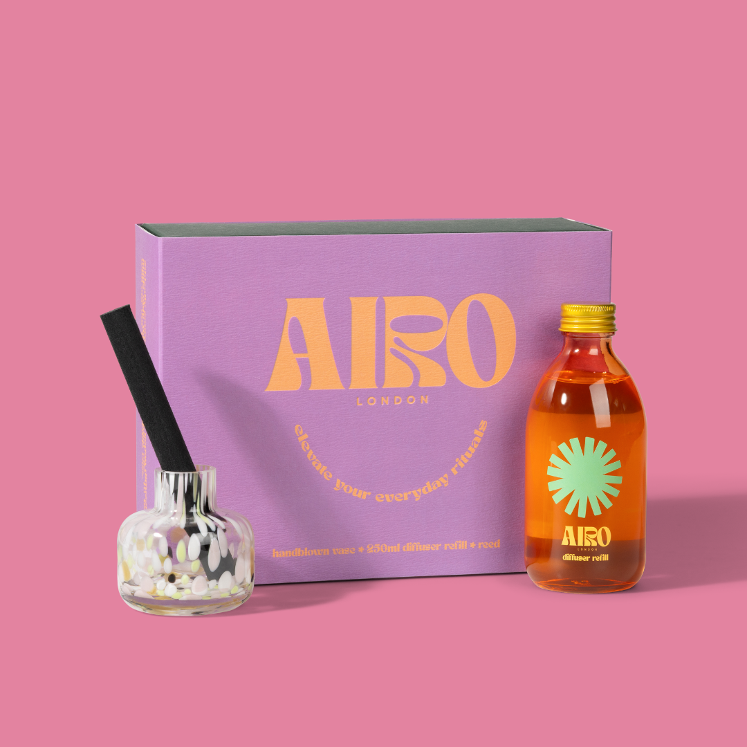 Airo London diffuser set with a purple box, glass diffuser, and bottle on a pink background