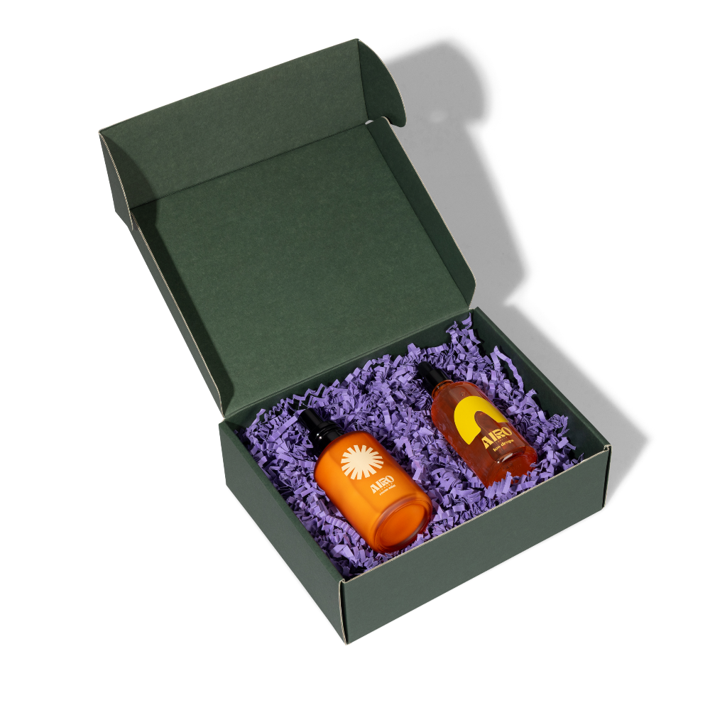 Two bottles in a green box with purple crinkle paper on a white background room fragrance and loo drops for home fragrance