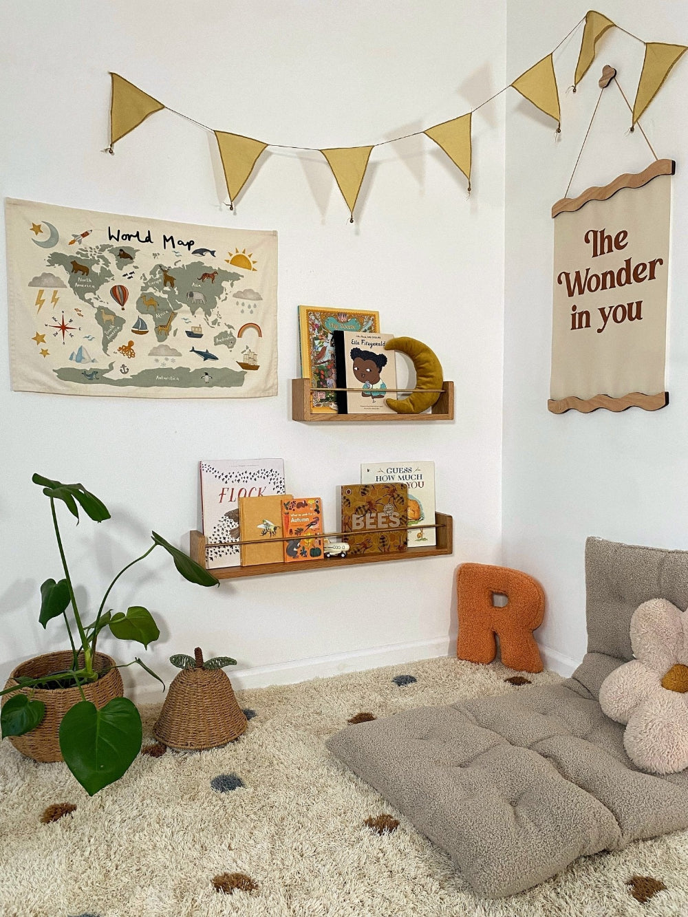 Children's room with world map, books, and decorative elements on a white wall.