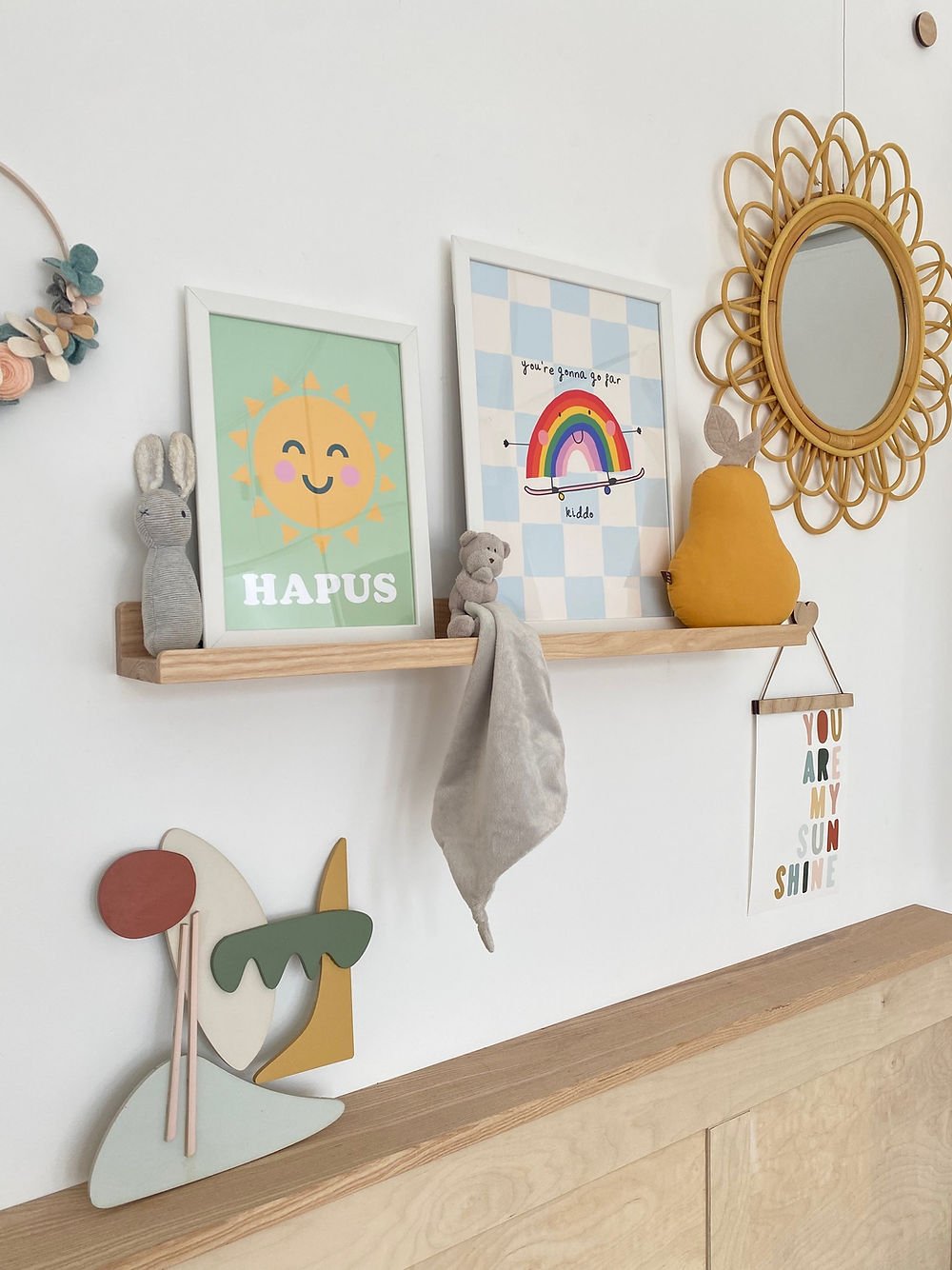 Nursery wall decor with framed pictures, a mirror, and wooden shelves.