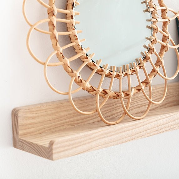 Wooden mirror on a wooden shelf against a light background