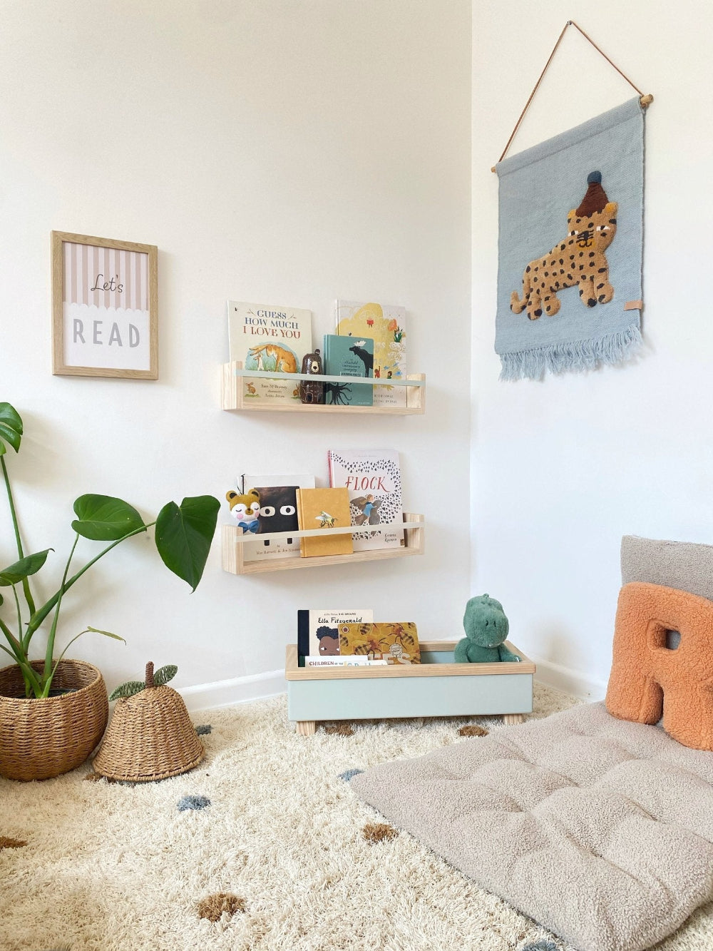 Children's room with shelves, books, and decorative items on a white wall.